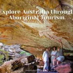 Travelers exploring Aboriginal rock art at a sacred site in Arnhem Land, guided by an Indigenous expert, showcasing authentic cultural tourism in Australia. With text reads as "Explore Australia through Aboriginal Tourism"