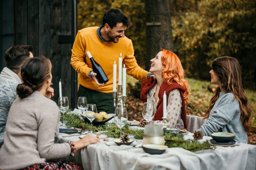 Friends enjoying wine at an autumn outdoor dinner party