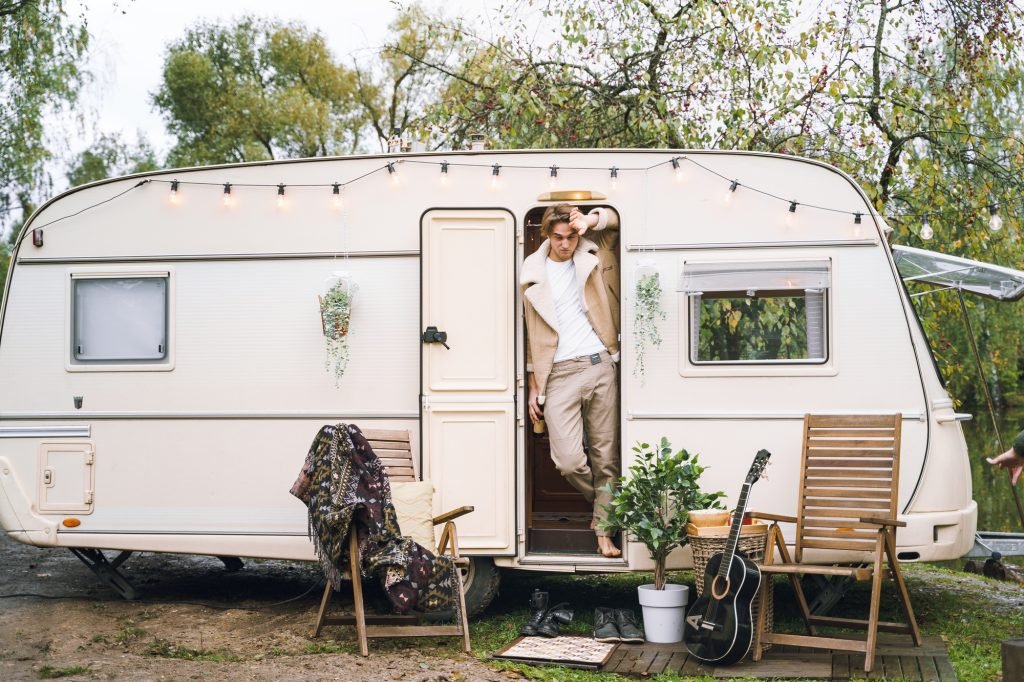 Young stylish american guy,man traveling in camper,house on wheels,trailer,motor home. Romantic road
