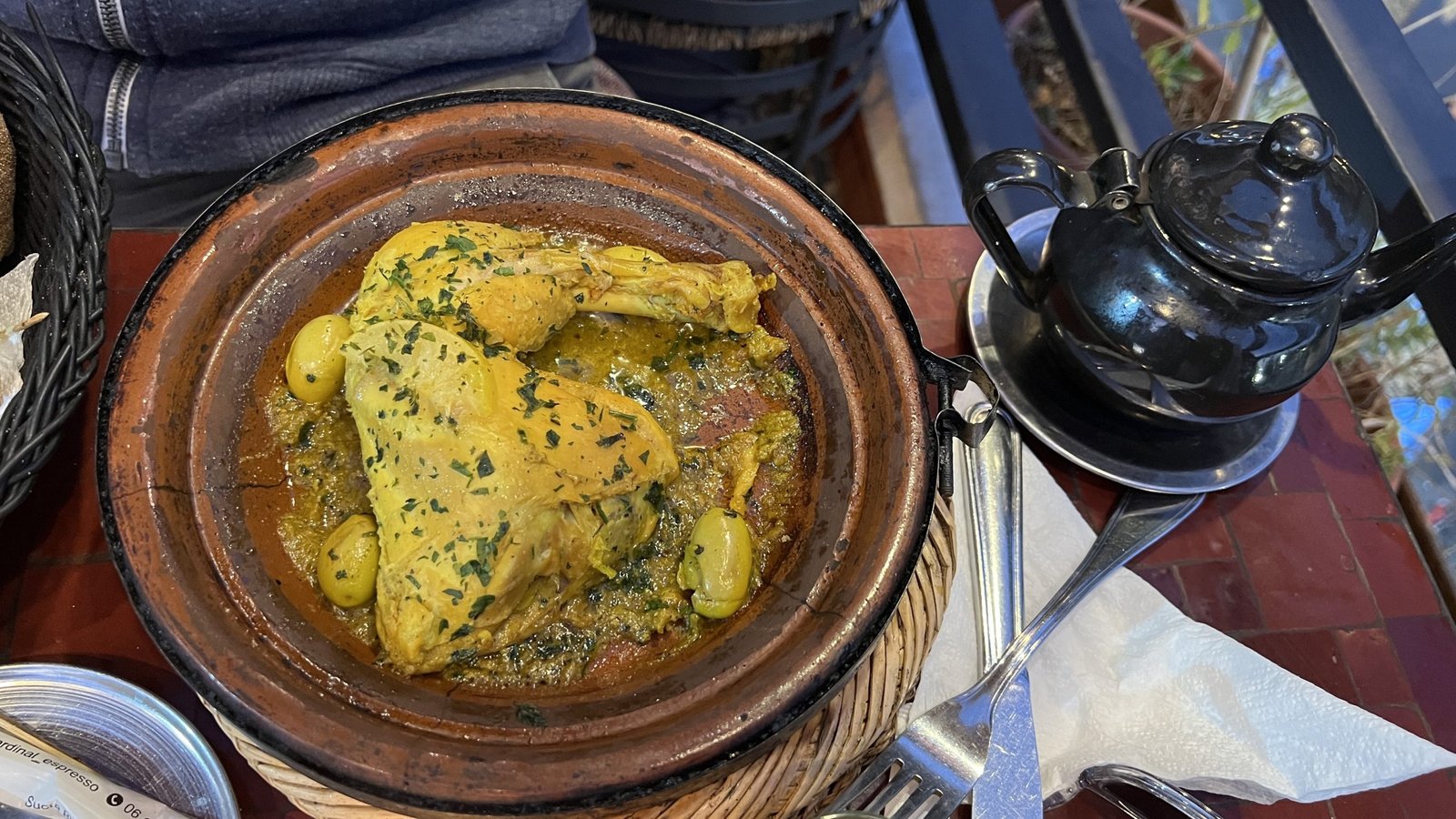 Traditional Moroccan chicken tagine with olives served in a clay pot alongside mint tea, a must-try dish during a 2 day in Marrakech food experience.