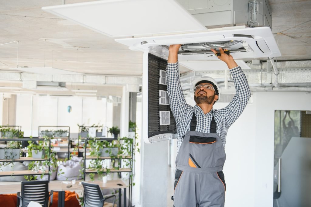 Concentrated young Indian engineer setting up air conditioner
