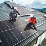 Men workers installing solar panels on roof of house.
