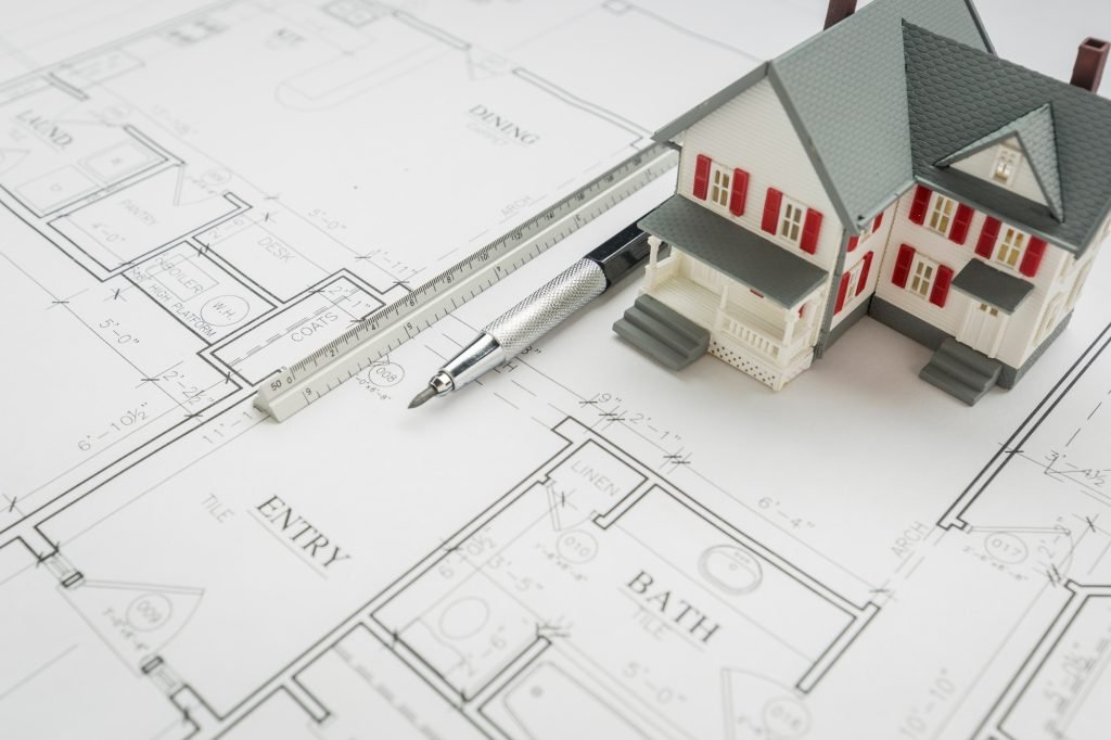 Model Home, Engineer Pencil and Ruler Resting On Custom House Plans.