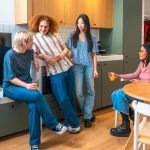 Roommates drinking orange juice and chatting in kitchen