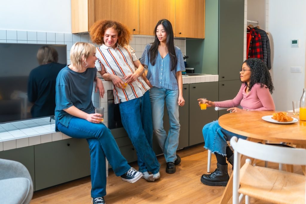 Roommates drinking orange juice and chatting in kitchen