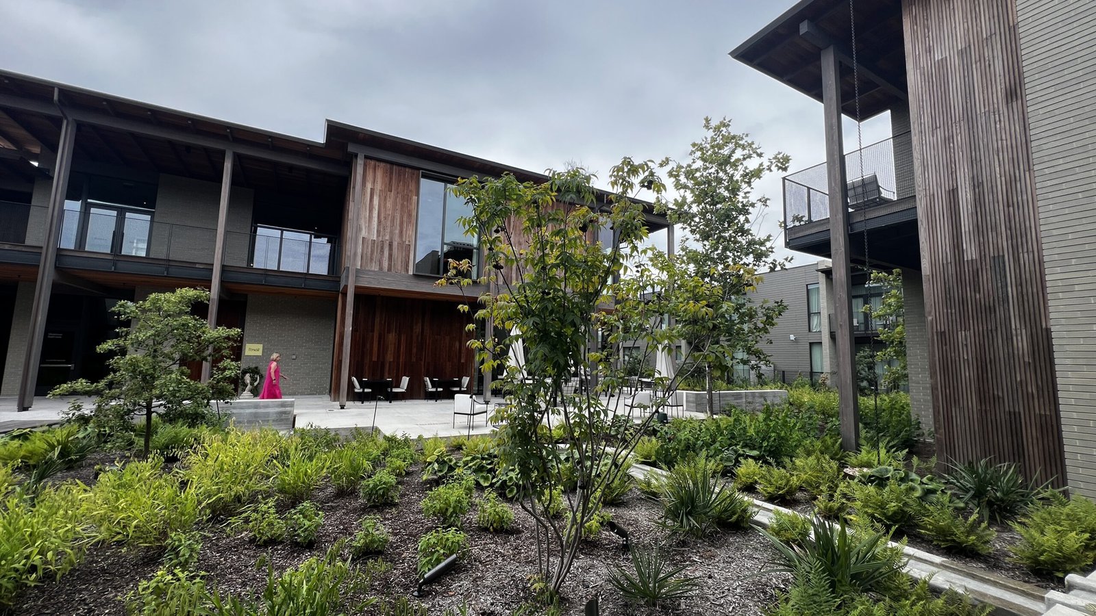Exterior view of Hotel Saint Augustine in Houston’s Montrose neighborhood, featuring modern wooden facades, large windows, balconies, and landscaped gardens.
