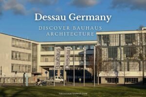 The Bauhaus building in Dessau, Germany, showcasing iconic modernist architecture with glass curtain walls and clean lines; banners reading 'Bauhaus Dessau' stand in front under a blue sky.