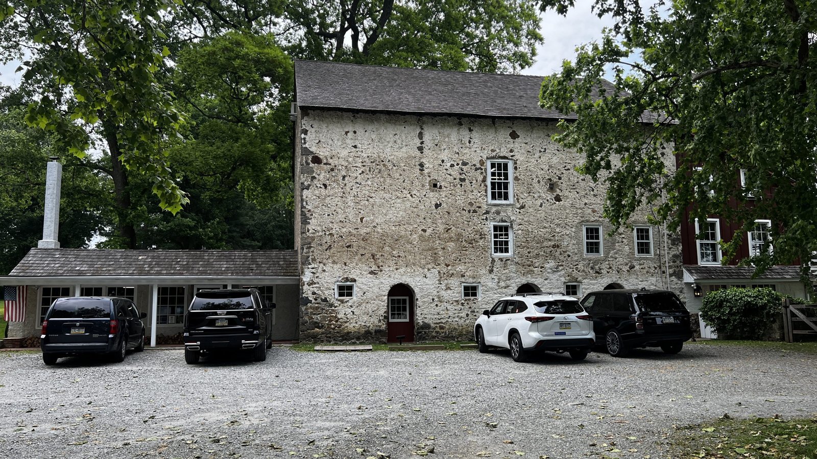 Baldwin’s Book Barn, one of Brandywine Valley’s Best Bookstores - with its historic stone exterior, surrounded by trees and parked cars in the gravel lot.