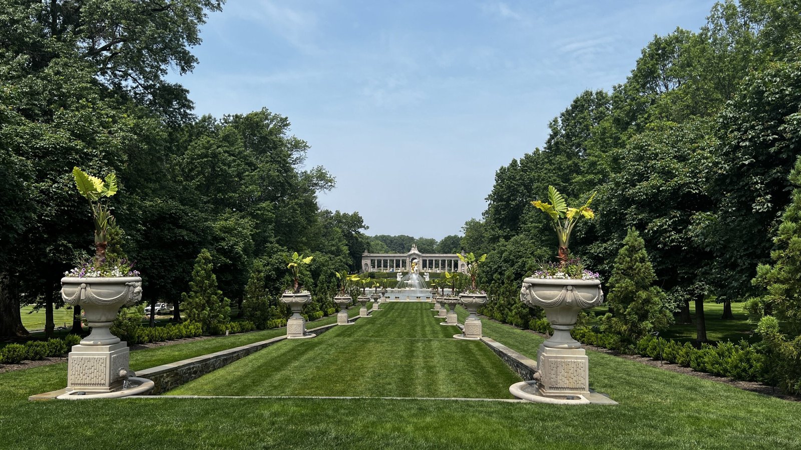 Grand formal lawn and fountain at Longwood, one of the iconic Brandywine Valley Gardens, lined with sculpted urns and lush greenery.