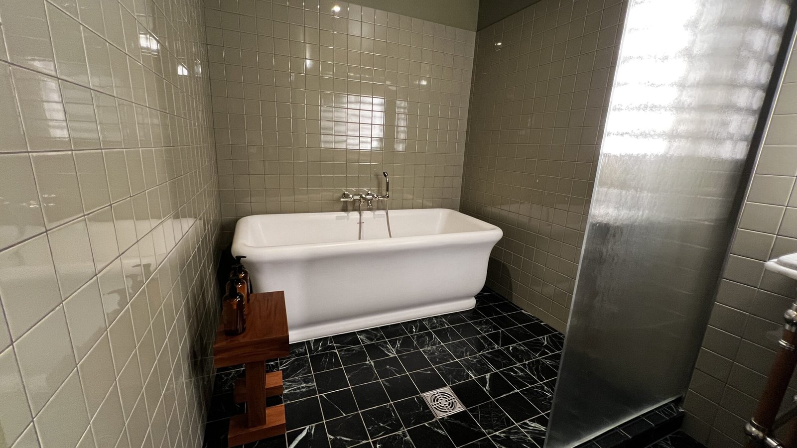Spacious bathroom with a white soaking tub, tiled walls, and black marble floor at Hotel Saint Augustine.