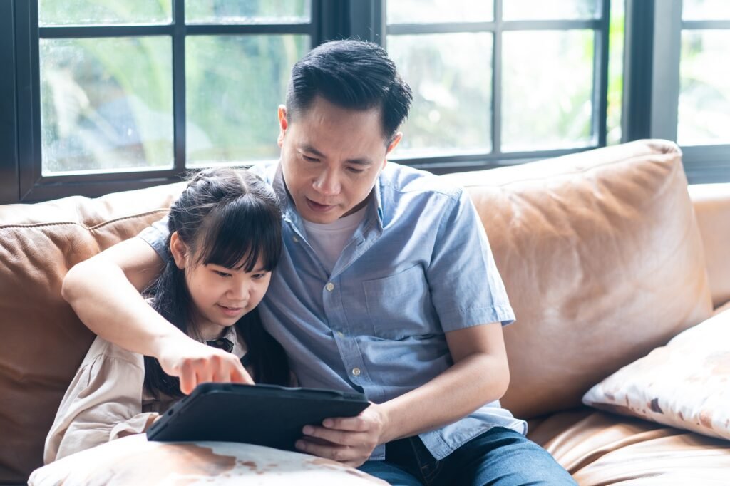 Asian family girl kid and father using tablet play internet online in living room