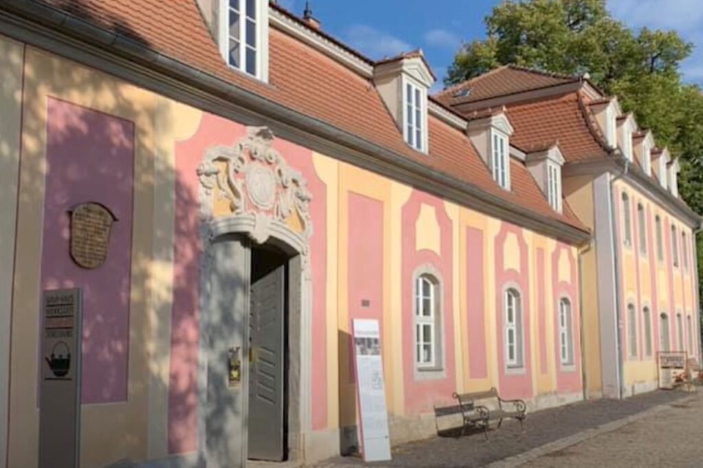 Exterior of the pink and yellow Dornburg Bauhaus ceramics building, formerly a castle stable, now housing historical design exhibits.
