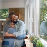 Embraced African American couple by the window at home.