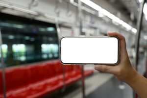 Hand holding smartphone with blank screen on public transportation
