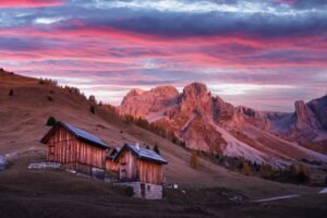 Wooden cabins, orange larches and mountains peaks