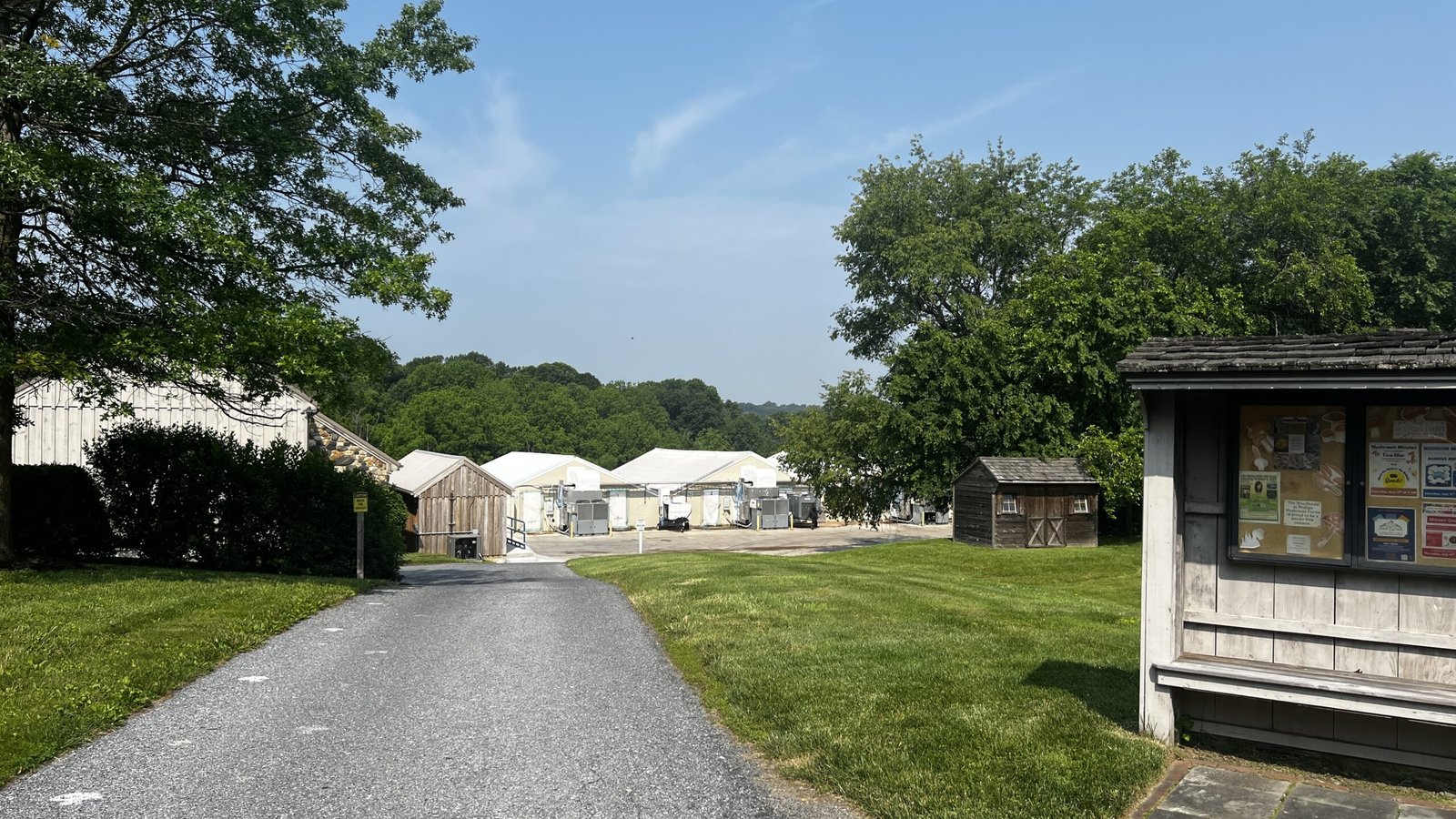 Kennett Square: Exploring the Mushroom Capital of the World Paved pathway leading past wooden sheds and white growing houses with trees in the distance.