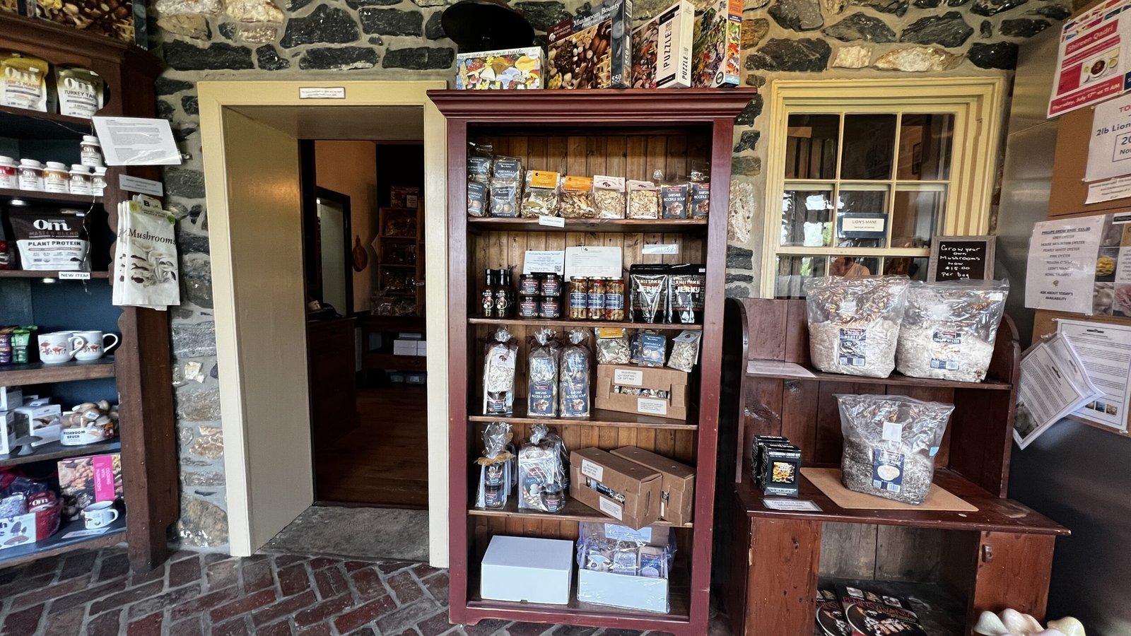 Kennett Square: Exploring the Mushroom Capital of the World Wooden shelves inside a stone-wall shop displaying packaged mushroom snacks, powders, and specialty goods.