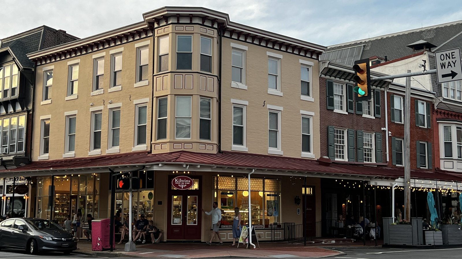 Corner view of Kilwins chocolate and ice cream shop with people gathered inside and outside.