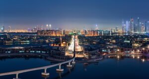 Cityscape of Dubai, United Arab Emirates at dusk, with illuminated skyscrapers in the distance and