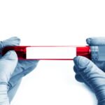 Close up of scientist hand with a blood ampoule