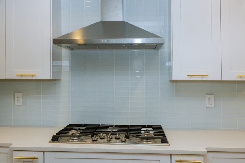 Kitchen features white cabinets with marble countertops paired with stone stainless steel hood
