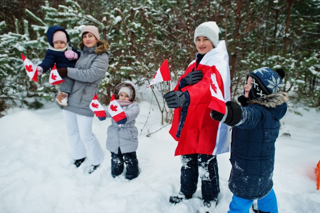 Mother with kids holding flag of Canada on winter landscape.