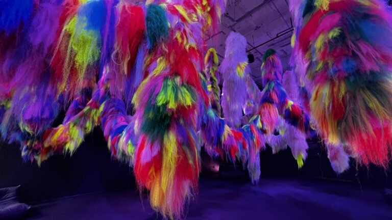Close-up view of Shoplifter’s Nervescape installation featuring cascading strands of neon faux hair in vivid colors like red, yellow, green, and purple.