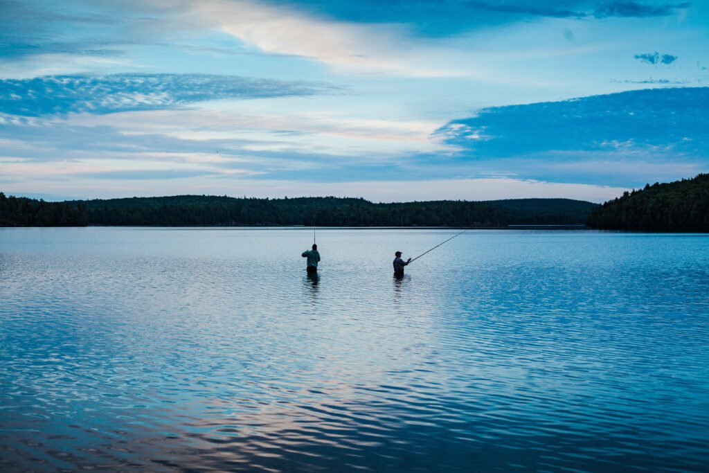 two men fishing calm lake blue sky scaled