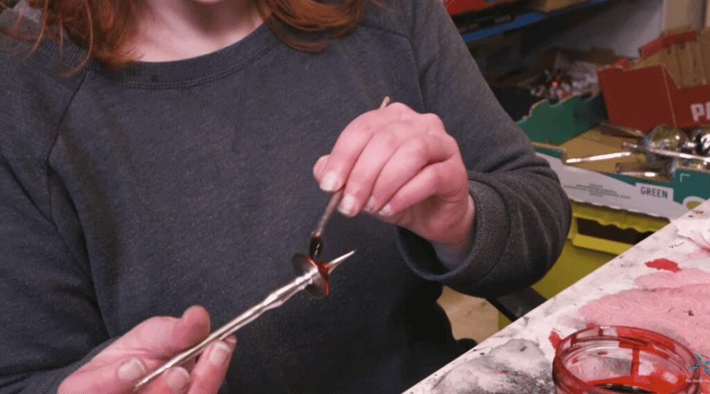 An artisan hand-paints a cooled glass ornament with detailed color accents in Lauscha.
