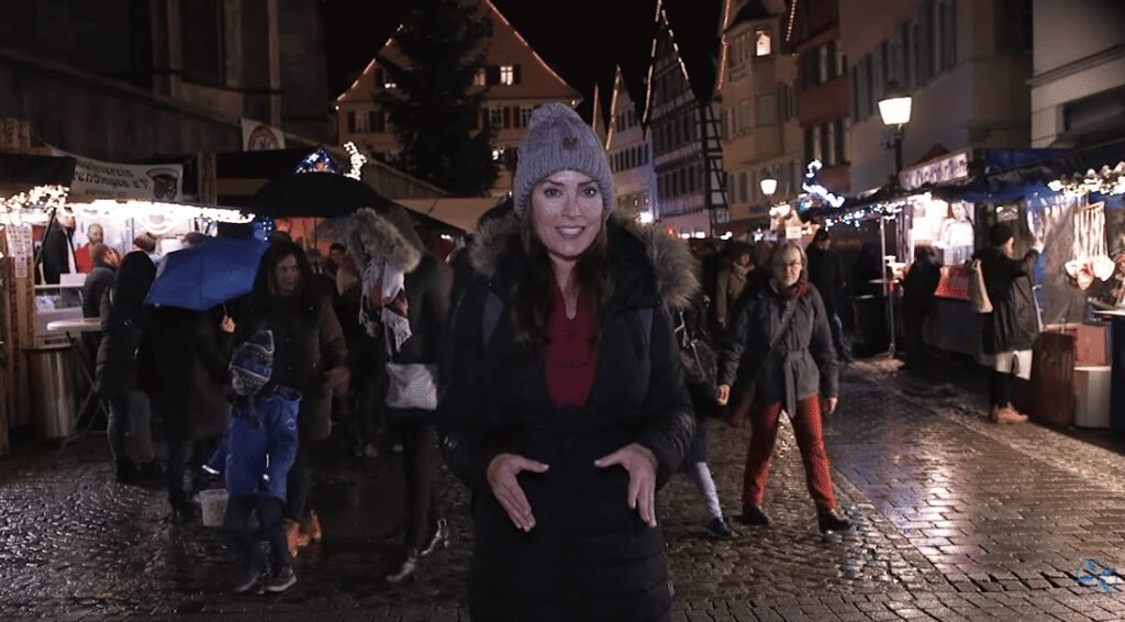 Karen stands in the middle of Tübingen’s festive Christmas market at night.