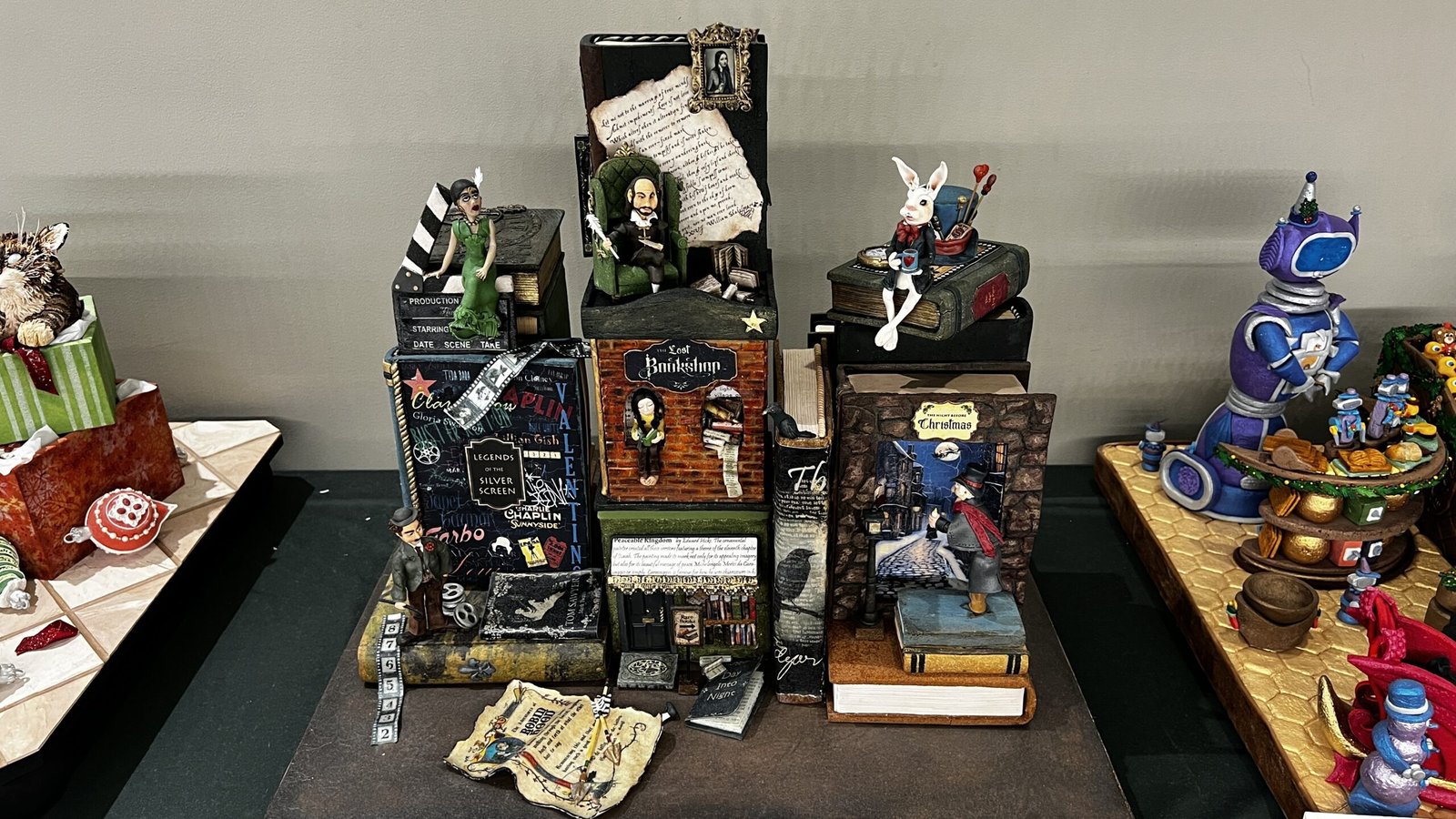 Gingerbread sculptures styled as stacked books and story scenes with figurines, displayed at the National Gingerbread House Competition inside the Omni Grove Park Inn & Spa.