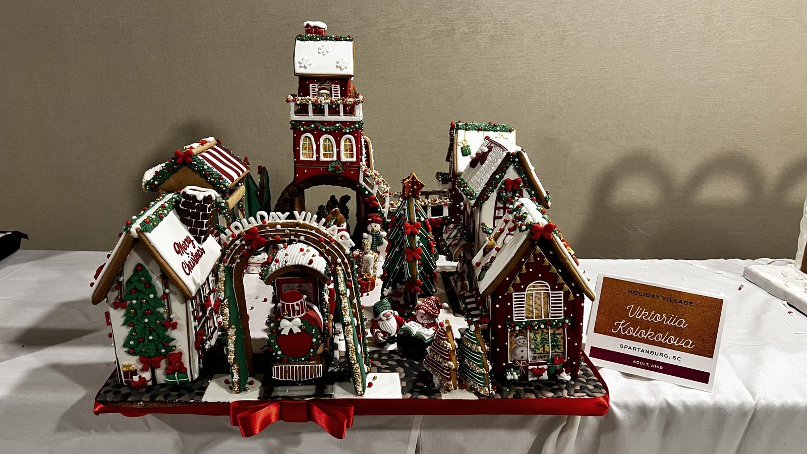 Handcrafted gingerbread village with small houses, holiday details, and figurines displayed at the National Gingerbread House Competition inside the Omni Grove Park Inn & Spa.