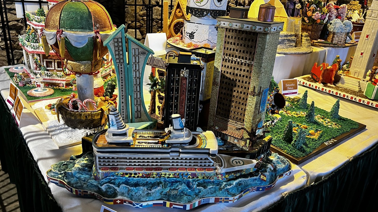 Large-scale gingerbread display featuring a cruise ship, city buildings, and detailed scenes at the National Gingerbread House Competition inside the Omni Grove Park Inn & Spa.