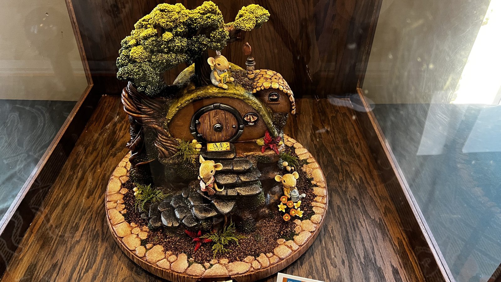 Fantasy-inspired gingerbread house with a rounded doorway, stone steps, and miniature figures displayed at the National Gingerbread House Competition inside the Omni Grove Park Inn & Spa.