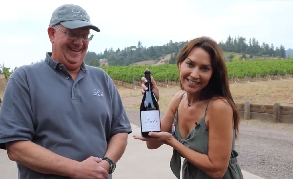 Karen LeBlanc and Chris Lanier of Lula Cellars holding a bottle of wine in the Anderson Valley vineyard.