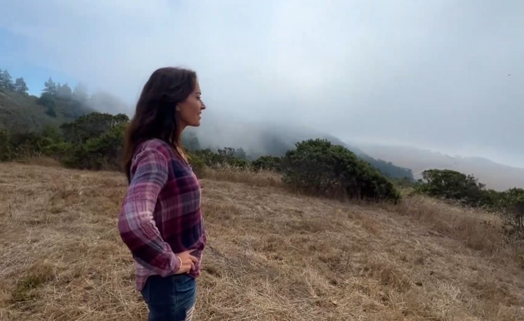 Karen stands on a high bluff overlooking the Mendocino Coast as fog drifts across the ridgetops.