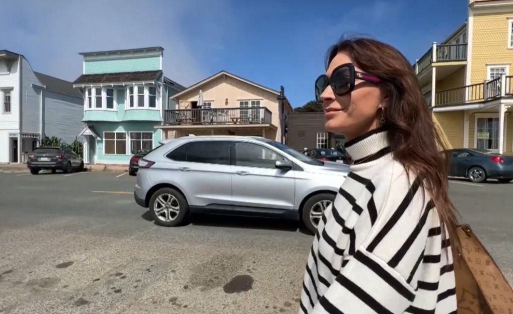 Karen walks through downtown Mendocino, wearing a striped sweater and sunglasses as she explores the coastal village’s historic storefronts.