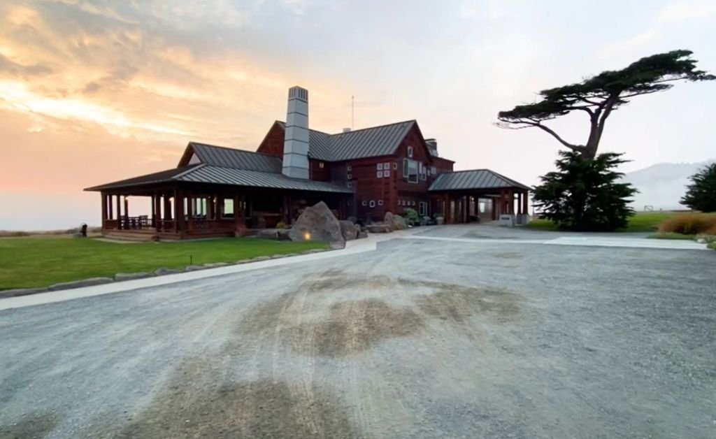 The Inn at Newport Ranch at sunset, with its rustic redwood architecture, wide porches and coastal landscape beneath a soft pastel sky.