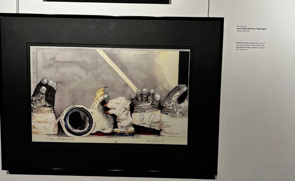 Watercolor print titled Don’t Think We’ll See Flight Again by Ron Woods, showing a row of astronaut gloves and spacesuit components.