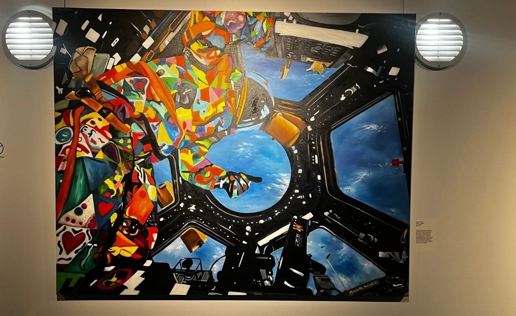 Colorful painting UNITY in Space by Annette Winkler showing the UNITY Art Spacesuit floating inside the International Space Station’s Cupola, with Earth visible through the windows.