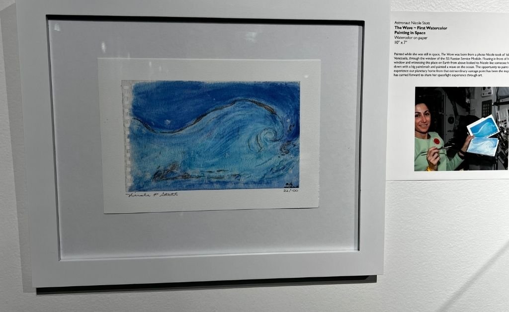 Framed watercolor painting titled The Wave by astronaut Nicole Stott, created in space and displayed at Orlando Science Center.