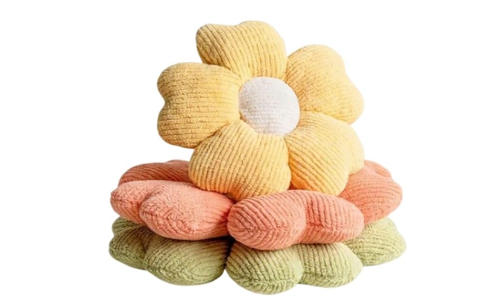 Stack of flower-shaped decorative throw pillows in soft yellow, peach, and green tones