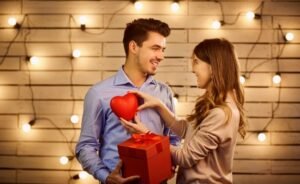 Valentine’s Day gift ideas shown as a couple exchanging a heart-shaped gift in a warm, romantic setting