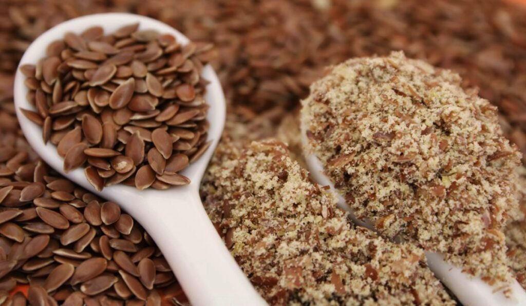 Whole and ground flaxseeds on two white spoons