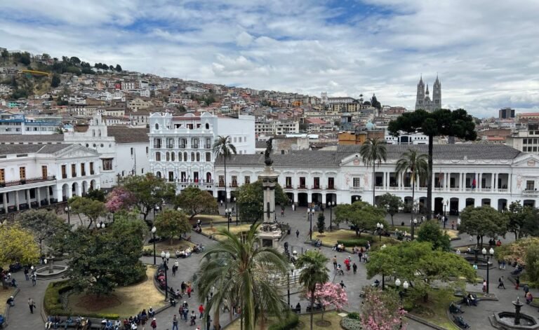 High-angle view of Plaza Grande in the historic center of Quito, Ecuador's Most Uderrated City featuring colonial architecture, a central monument, and the Basilica del Voto Nacional in the background.