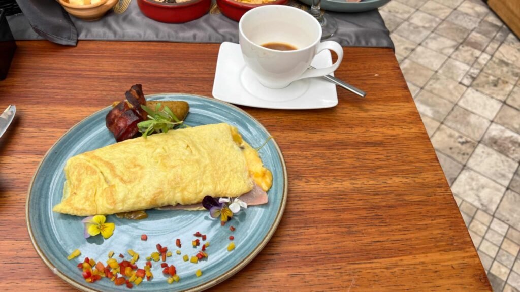 A beautifully plated ham and cheese omelet served with crispy bacon on a wooden table at a luxury boutique hotel restaurant in Quito Ecuador